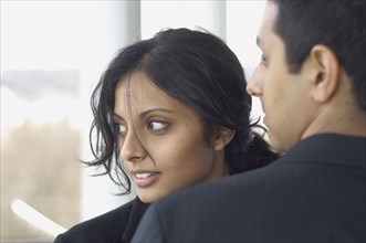 Middle Eastern businesswoman looking over man's shoulder