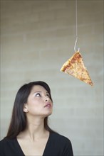 Asian woman looking at pizza on hook