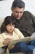 Hispanic father reading to daughter
