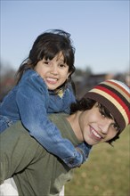 Hispanic boy giving sister piggyback ride