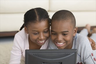 African brother and sister looking at laptop