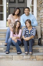 Hispanic family sitting on porch steps