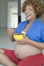 Pregnant African woman eating cereal
