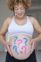 Pregnant African woman with question marks painted on belly