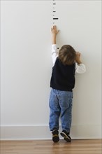 Boy reaching for height markers on wall