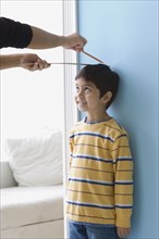 Asian boy having height measured on wall