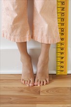 Girl standing on tiptoes next to ruler