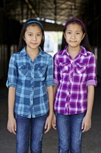 Asian twin girls smiling in barn