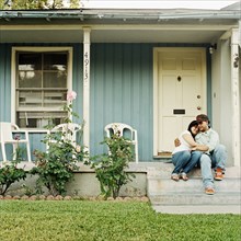 Couple hugging on front stoop of house