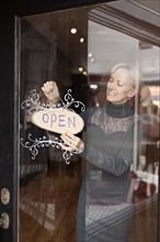 Caucasian small business owner hanging open sign on front door
