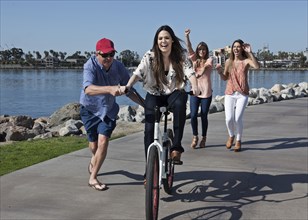 Man pushing woman on bicycle at waterfront