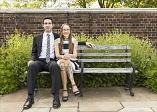 Well-dressed Caucasian couple sitting on bench at park