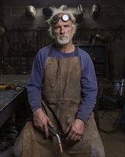 Portrait of serious Caucasian blacksmith in workshop holding torch