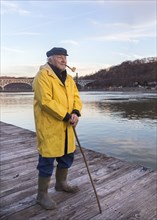 Older Caucasian fisherman standing on dock