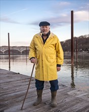 Older Caucasian fisherman standing on dock