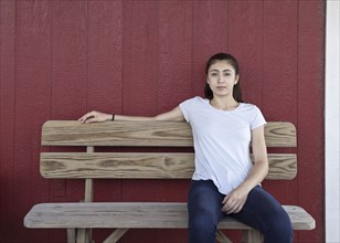 Portrait of serious Caucasian girl sitting on bench