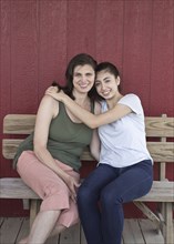 Portrait of smiling Caucasian girl hugging mother on bench
