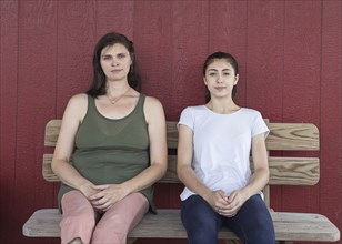 Portrait of serious Caucasian girl and mother on bench