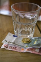 Empty glass and Euro notes and coins
