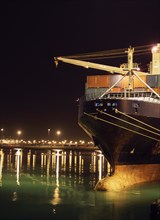 Illuminated crane and container ship at night