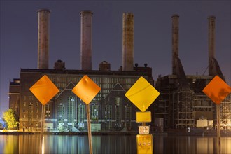 Warning signs and factory smokestacks lit up at night