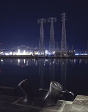 Reflection of metal towers in harbor at night