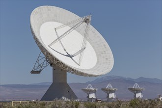 Satellite dishes in field near mountain range