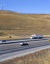 Cars and trucks driving on freeway near wind farm