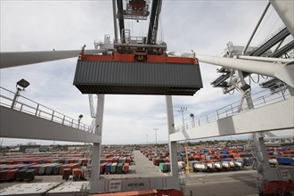 Crane lifting cargo container at port