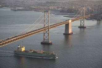 Aerial view of freighter under urban bridge