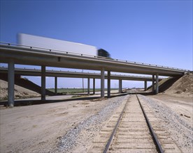 Trucks driving on freeway overpass over train track