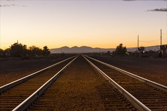 Railroad tracks in mountain landscape at sunset