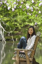 Asian woman sitting on bench in park
