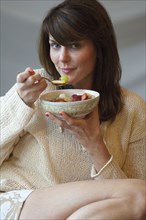 Caucasian woman eating bowl of fruit