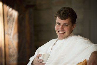 Caucasian man drinking coffee in bathrobe