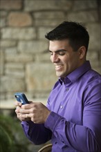 Hispanic businessman using cell phone indoors
