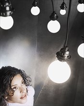 Young woman looking up at a light bulb