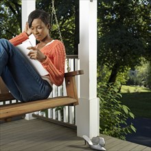 Mixed race woman reading on porch