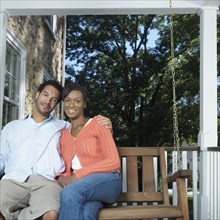 Mixed race couple sitting on porch swing