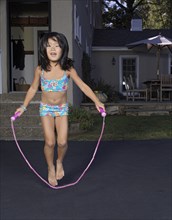 Korean girl jumping rope in driveway