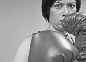 Mixed race boxer holding gloves in front of face