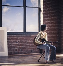 Caucasian woman playing guitar in living room