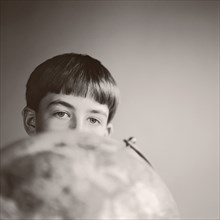 Boy peering over globe