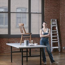 Mixed race woman painting chair in loft