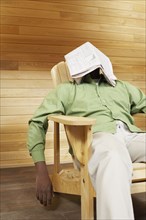African man with newspaper over face