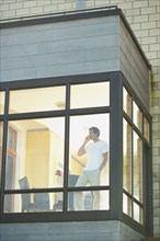 Man talking on cell phone next to window