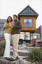 Couple holding wine in front of house