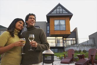 Couple holding wine in front of house