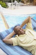 African man laying in hammock at poolside
