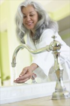 Smiling woman checking water temperature in spa